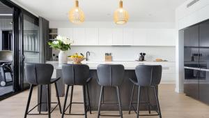 a kitchen with gray chairs and a kitchen island at Luxe by the Lake in Lake Illawarra