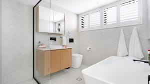 a white bathroom with a sink and a toilet at Luxe by the Lake in Lake Illawarra