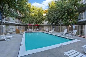a swimming pool in a courtyard with chairs and trees at Motel 6-Sunnyvale, CA - North in Sunnyvale
