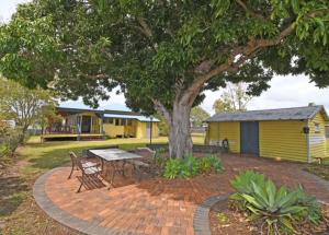 a picnic table under a tree next to a yellow house at Torquay Treasure in Torquay