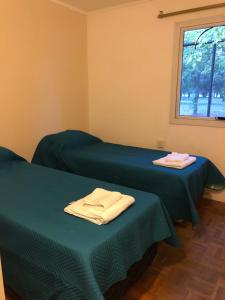 2 camas en una habitación con sábanas verdes y una ventana en Alojamiento en San Rafael en San Rafael