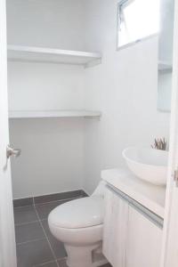 a white bathroom with a toilet and a sink at Espectacular apartamento Duplex VIP 501 con jacuzzy in Sabaneta
