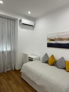 ein weißes Schlafzimmer mit einem Bett und einem Fenster in der Unterkunft CASA DA PRAIA DA POÇA - APARTAMENTO LÍRIO in Estoril