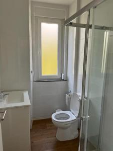 een badkamer met een toilet, een wastafel en een raam bij CASA DA PRAIA DA POÇA - APARTAMENTO LÍRIO in Estoril