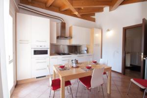 a kitchen with a wooden table and white cabinets at Casa del Sole - sleeps 4 with shared pool in Pianello Del Lario