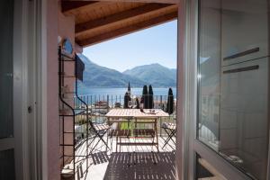 a balcony with a table and chairs and a view of the water at Casa del Sole - sleeps 4 with shared pool in Pianello Del Lario