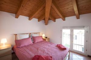 a bedroom with a large bed with pink sheets at Casa del Sole - sleeps 4 with shared pool in Pianello Del Lario