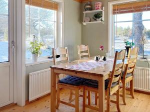 a wooden table and chairs in a room with windows at Holiday home LIDKÖPING VIII in Tallbacken