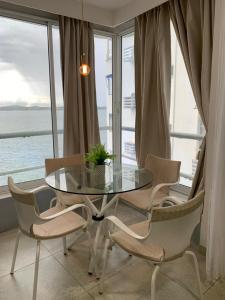 una mesa de cristal y sillas en una habitación con ventana en APARTASUITES CON VISTA AL MAR en Cartagena de Indias