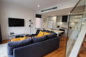 a living room with a blue couch and yellow pillows at Flagstaff Hill West Melbourne in Melbourne