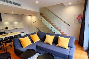 a living room with a blue couch with yellow pillows at Flagstaff Hill West Melbourne in Melbourne
