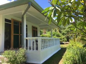 a white house with a porch at Pension Te Aroha - Te Arii in Maatea