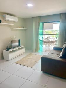 uma sala de estar com um sofá e uma televisão em Apartamento c/ piscina , Praia do Francês. em Marechal Deodoro