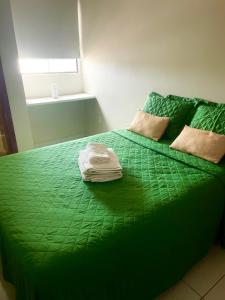 uma cama verde com duas toalhas em cima em Apartamento c/ piscina , Praia do Francês. em Marechal Deodoro