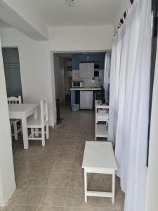 Habitación con mesas y sillas blancas y cocina. en CasaBlanca alq. Deptos en San Salvador de Jujuy