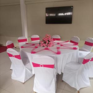 a white table with white chairs and a table with pink ribbon at International Hotel, Yaoundé in Yaoundé