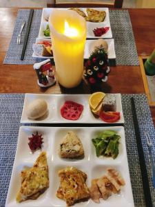 Xin Yuan Hang Homestay في قوانشان: طاولة مع أطباق من الطعام وشمعة