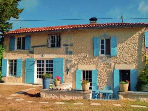 a stone house with blue shutters and chairs in front at Spacious holiday home with pool in Lusignac in Bouteilles-Saint-Sébastien