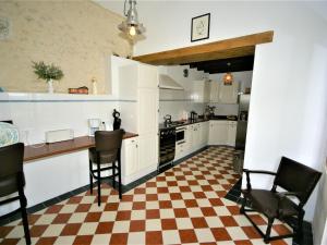 a kitchen with black chairs and a checkered floor at Spacious holiday home with pool in Lusignac in Bouteilles-Saint-Sébastien