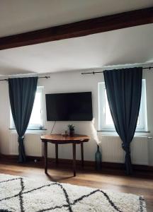 ein Wohnzimmer mit einem Tisch und blauen Vorhängen in der Unterkunft Elias im Landhausstil in Bayreuth
