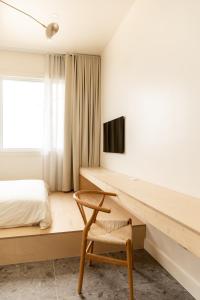 a bedroom with a desk and a bed and a chair at Petit hôtel de la Montagne in Havre-Aubert