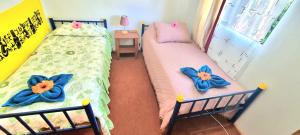 2 camas individuales en un dormitorio con flores azules. en Cabañas Henua Roa en Hanga Roa