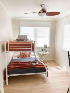 a bedroom with a bunk bed and a ceiling fan at Seaside Serenity~GamesRoom~HotSpa! in Port Macquarie