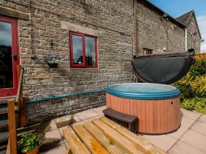 a hot tub and a wooden bench next to a building at Pine Cottage - Rchp140 in Calton