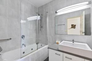 a bathroom with a sink and a tub and a mirror at White Crest Apartments in Hervey Bay