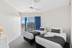 two beds in a room with a balcony at White Crest Apartments in Hervey Bay