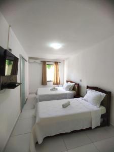 een hotelkamer met 2 bedden en een televisie bij Pousada Marihá in Piranhas