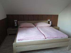 un letto con lenzuola rosa e 2 cuscini rosa di Penzion Fryštátská Chalupa a Karviná