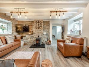 a living room with leather furniture and a stone wall at Old Stables Cottage in Blaenporth
