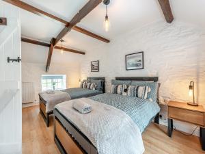 two beds in a bedroom with a brick wall at Old Stables Cottage in Blaenporth