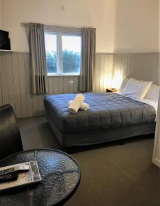 a hotel room with a bed with a table and a window at Kings Ohakune in Ohakune
