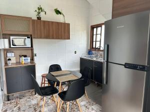 a kitchen with a table and a refrigerator at Recanto Pé na Areia SC in Palhoça