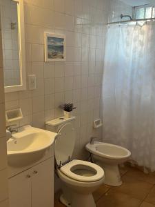 La salle de bains blanche est pourvue de toilettes et d'un lavabo. dans l'établissement La Jarilla, à Mendoza