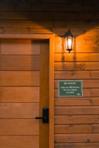 a sign on the door of a wooden building with a light at Cabanas nos Canyons in Praia Grande