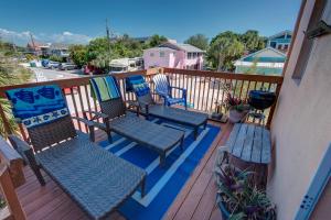 a balcony with three chairs and a bench on a deck at Lovely Gulf View Walk To Beach All Appliances in Bradenton Beach