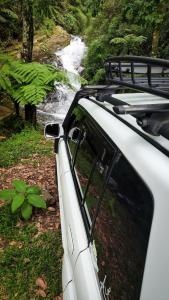 een witte auto geparkeerd voor een waterval bij Rancho Pedra do Picú in Itamonte