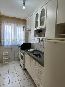 una cocina con armarios blancos y fregadero en Água das Fontes, en Caldas Novas