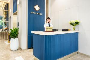a man talking on a phone at a reception desk at Jovia Hotel in Ho Chi Minh City