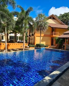 una piscina di fronte a una casa con palme di Du-sila Hotel kohchang a Ko Chang