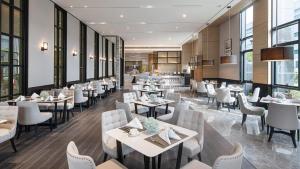 un restaurante con mesas, sillas y ventanas en Yiho Hotel Mawei Fuzhou en Fuzhou