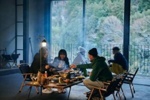 een groep mensen die aan een tafel eten bij 目の前が吉野川・雨天でも屋外体験ができる絶景の一軒家 in Ōtakuchi