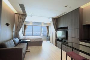 a room with a couch and a bed and a television at CM+ Hotels and Serviced Apartments in Hong Kong