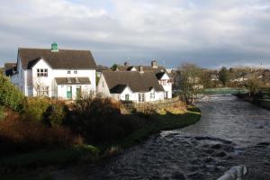 a group of houses on a hill next to a river at Achill in Bushmills