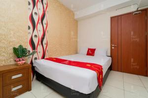 1 dormitorio con 1 cama con manta roja y blanca en RedLiving Apartemen Green Lake View Ciputat - Hanna Property Tower B en Pondokcabe Hilir