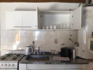 Una cocina con gabinetes blancos, un fregadero y una estufa. en El Amparo, en Esquel