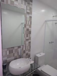 a bathroom with a sink and a toilet and a mirror at Saquarema Itauna em frente a praia in Saquarema